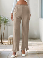 Person wearing beige pants with a white top indoors.