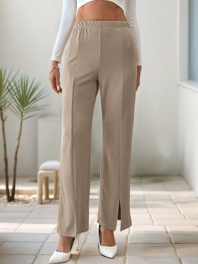 Person wearing beige pants with a white top indoors.