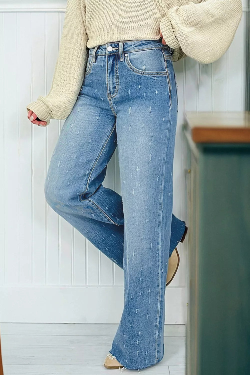 Person wearing blue jeans and a beige sweater in a kitchen setting