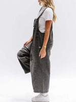 Person wearing gray denim overalls on a white background