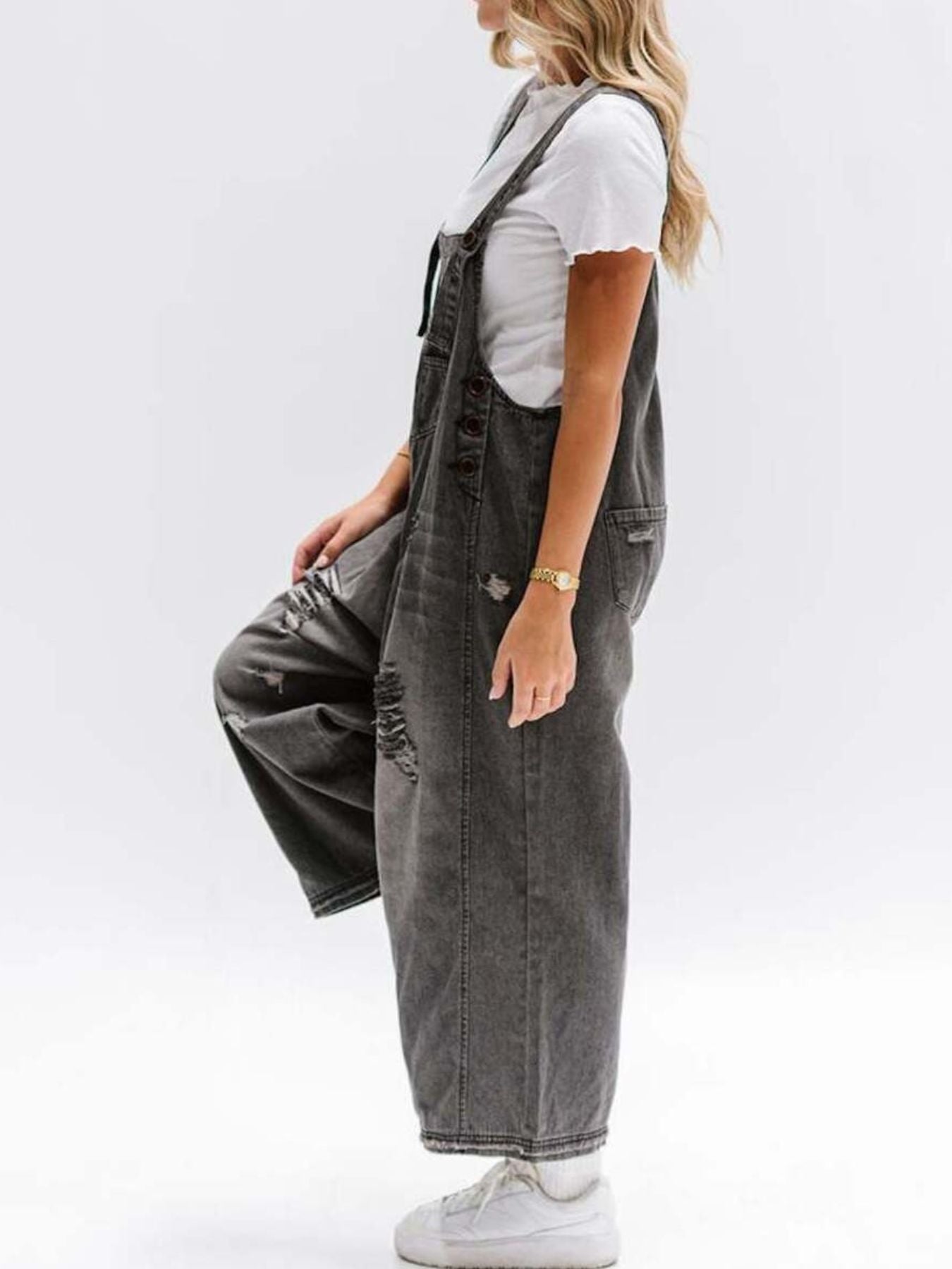 Person wearing gray denim overalls on a white background