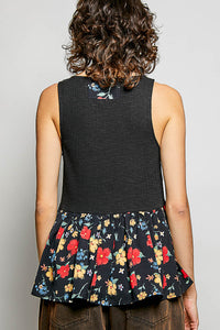 Person wearing a black sleeveless top with floral skirt on a plain background
