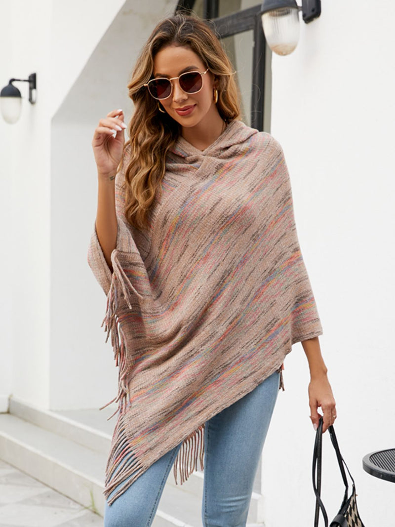 Woman wearing a striped poncho and sunglasses outdoors.