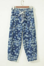 Blue floral-patterned pants on a hanger against a white background