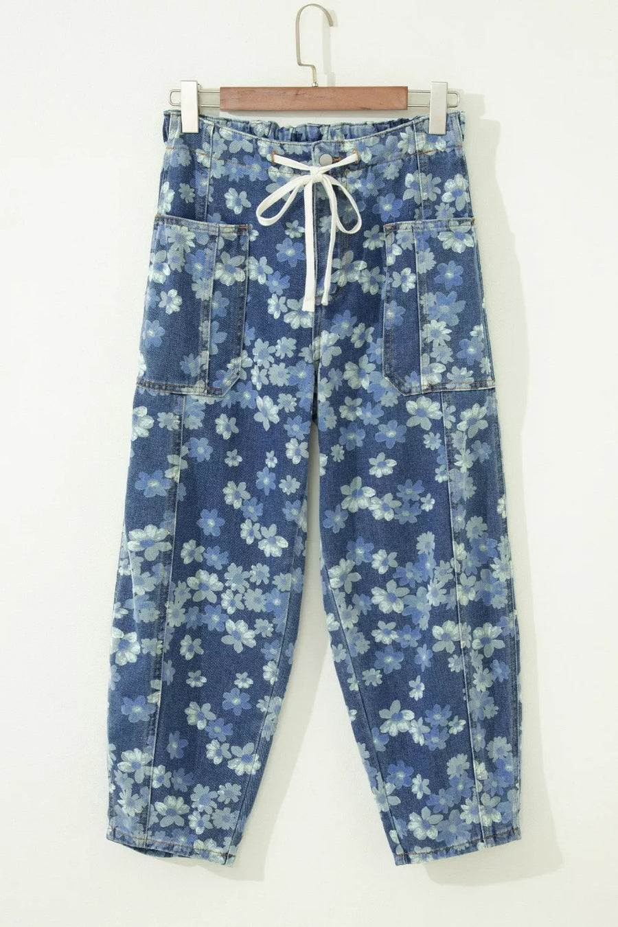 Blue floral-patterned pants on a hanger against a white background