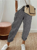 Person wearing striped pants and white sneakers with a beige bag indoors.