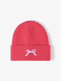 Red beanie with a white bow design on a light pink background