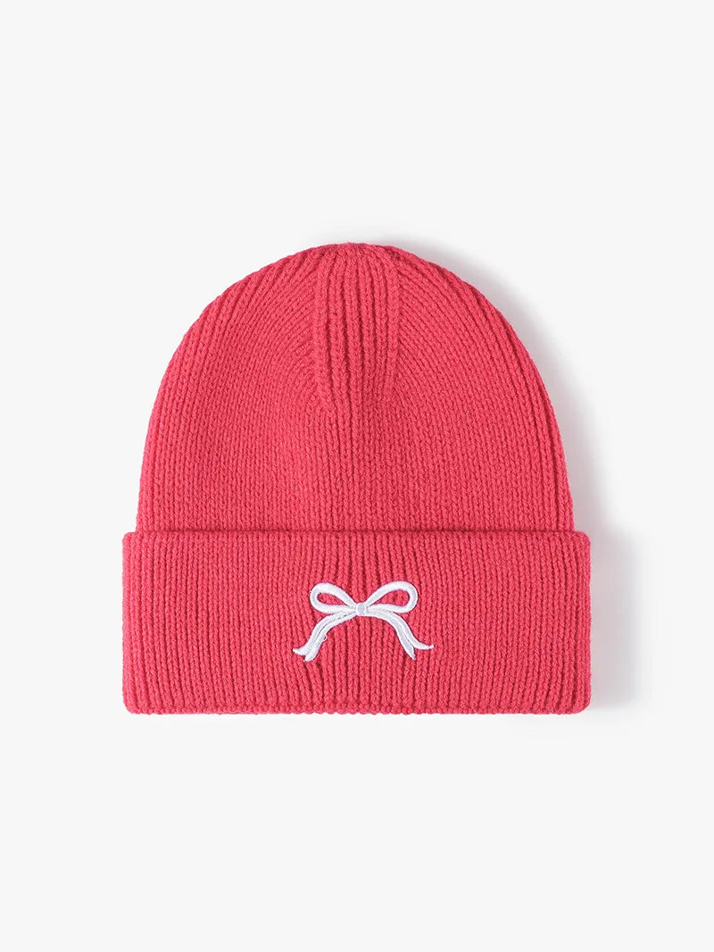 Red beanie with a white bow design on a light pink background