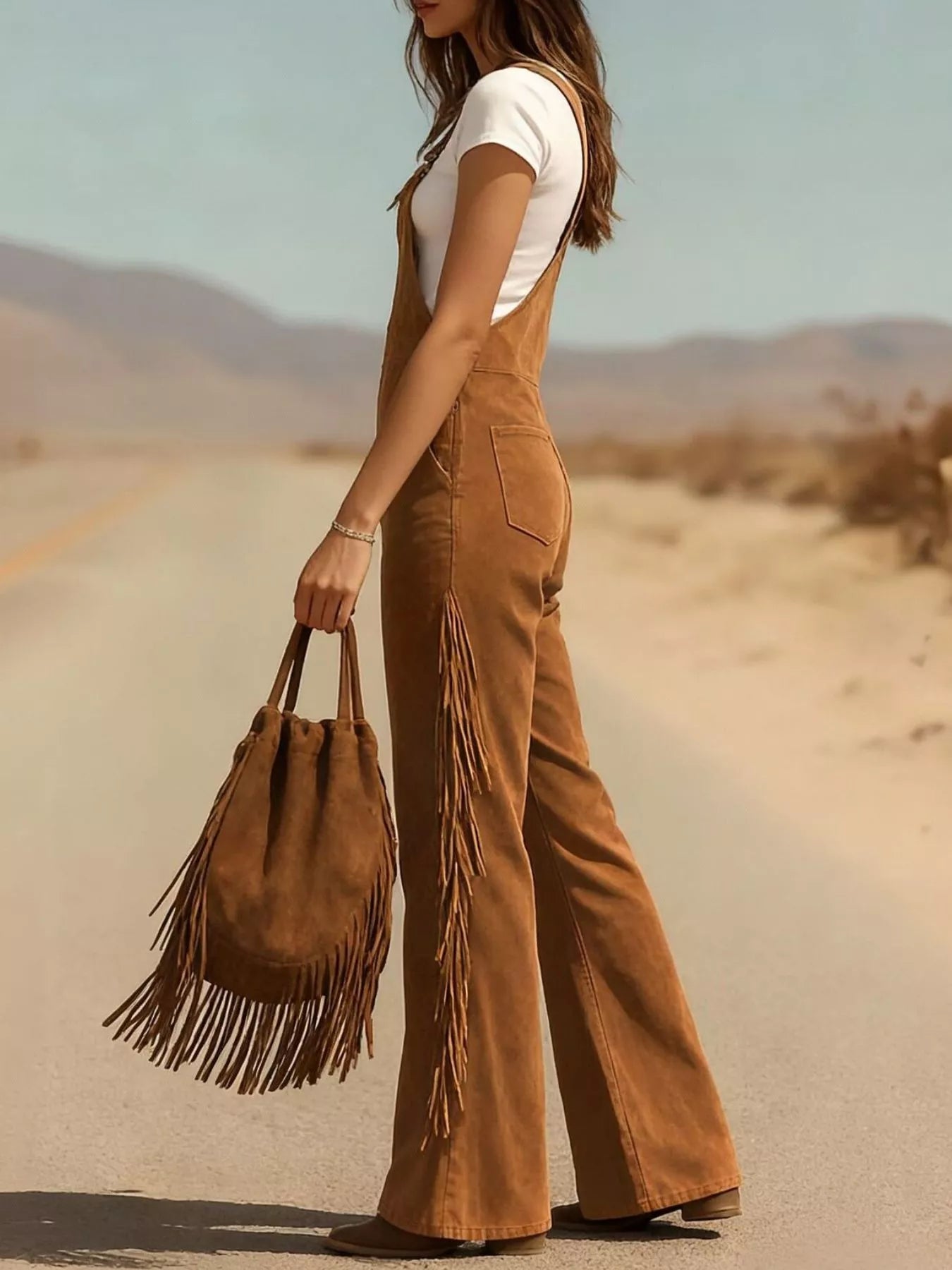 Person wearing brown fringed overalls and holding a matching bag in a desert setting