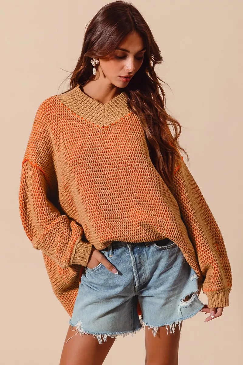 Woman wearing a mustard yellow sweater and denim shorts on a beige background