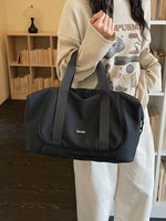 Person holding a black duffel bag in a room with wooden shelves.