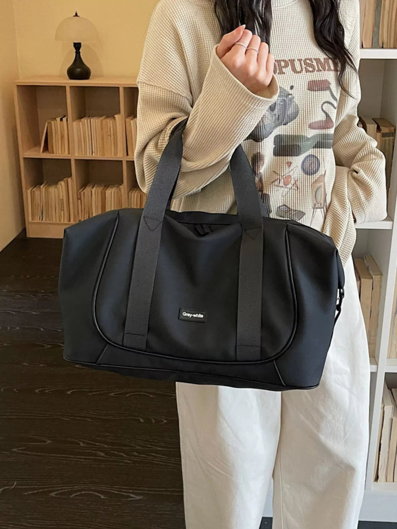 Person holding a black duffel bag in a room with wooden shelves.