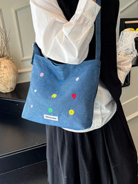 Person wearing a blue bag with colorful polka dots and a visible brand logo.