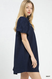 Woman wearing a navy blue dress with puff sleeves on a white background