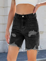 Black distressed denim shorts worn by a person with a blurred background