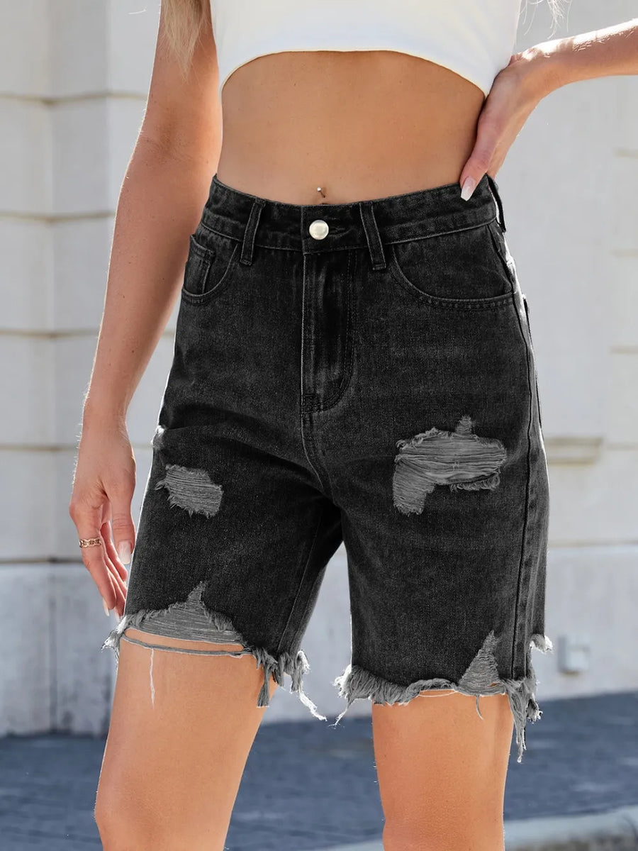 Black distressed denim shorts worn by a person with a blurred background