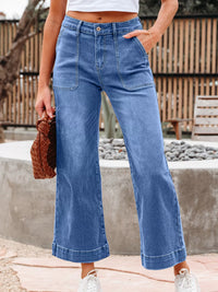 Person wearing blue wide-leg jeans with a blurred background