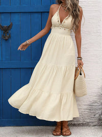 Woman in a beige dress standing in front of a blue door.