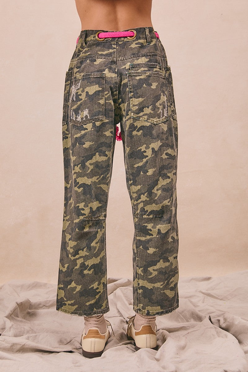Camouflage pants with a pink belt on a neutral background
