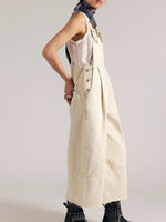Person wearing a beige overalls with a plain background