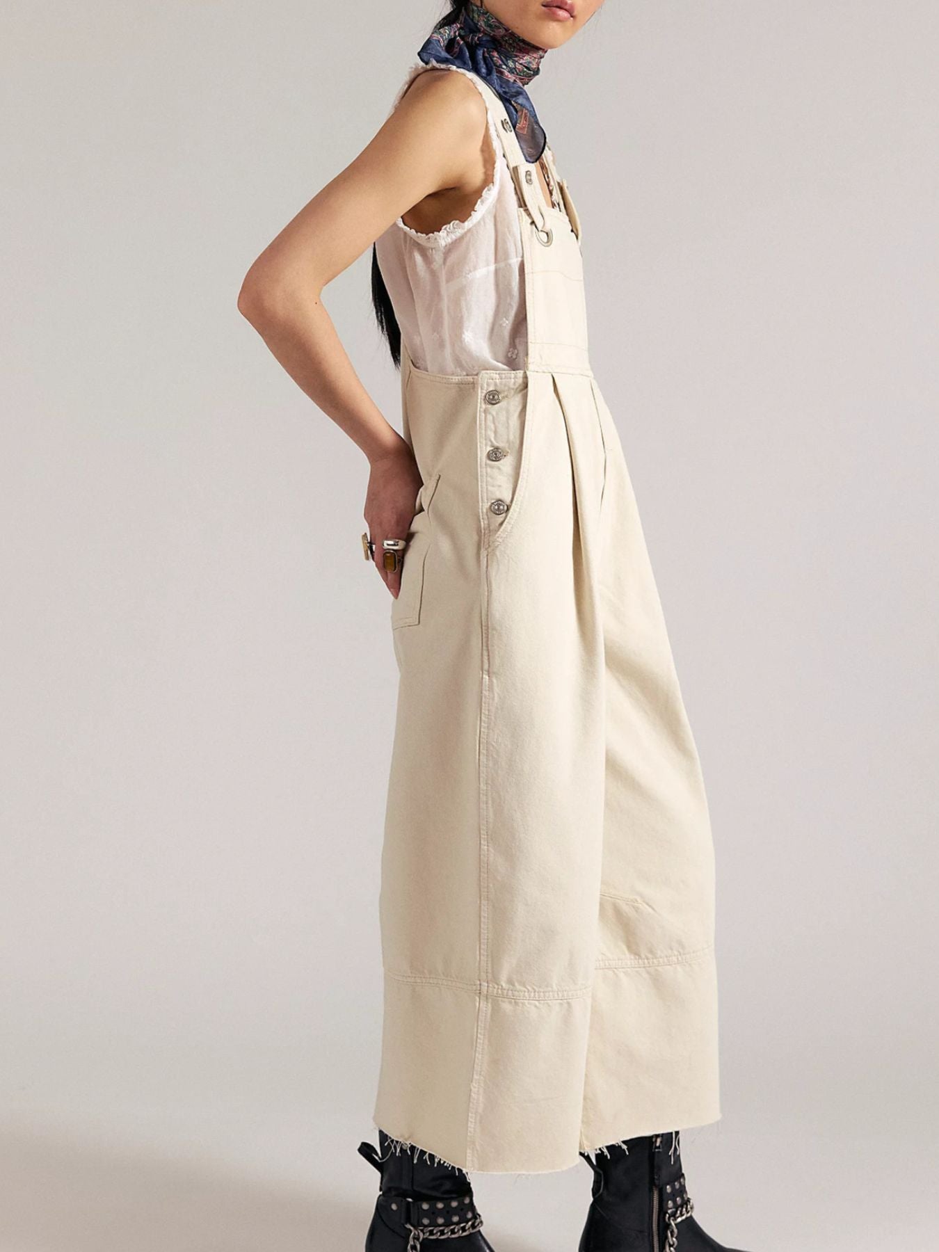 Person wearing a beige overalls with a plain background