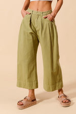Person wearing green wide-leg pants on a beige background