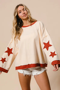 Woman wearing a cream sweater with red star patterns on a beige background