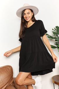 Woman wearing a black dress and white hat in a casual setting with a plant in the background