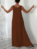 Brown sleeveless dress worn by a person against a white wall.