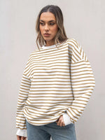 Woman wearing a white and beige striped sweater against a plain background