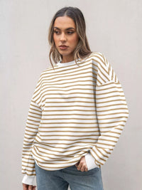 Woman wearing a white and beige striped sweater against a plain background