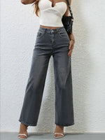 Person wearing high-waisted dark jeans and a white top against a light gray background