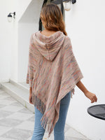 Woman wearing a colorful poncho walking outdoors on a sunny day.