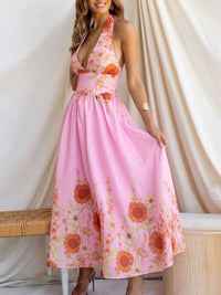 Woman wearing a pink floral dress standing against a white curtain.