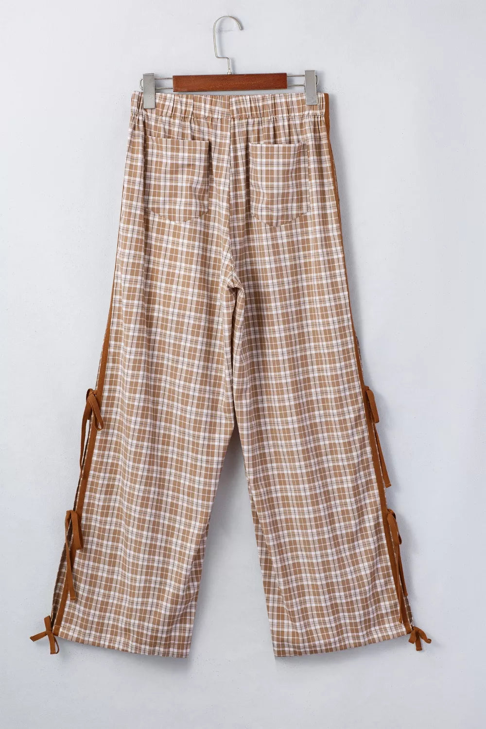 Plaid pants with brown accents hanging on a white background