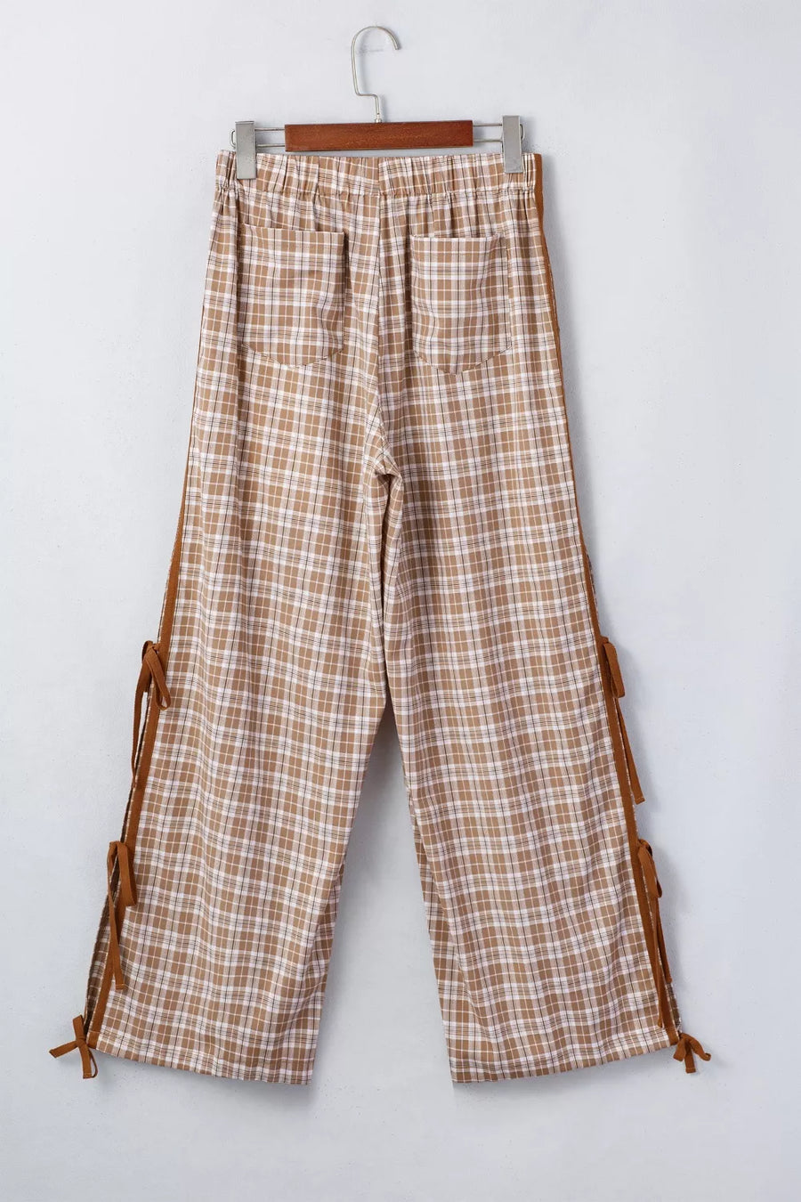 Plaid pants with brown accents hanging on a white background
