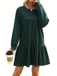 Green dress with long sleeves and ruffled hem worn by a person holding a coffee cup on a white background