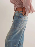Person wearing a light pink blouse and blue jeans on a plain background