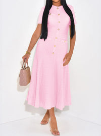 Woman wearing a pink dress with gold buttons on a white background