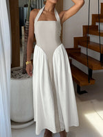 Woman wearing a beige halter neck dress with a white skirt in an indoor setting.