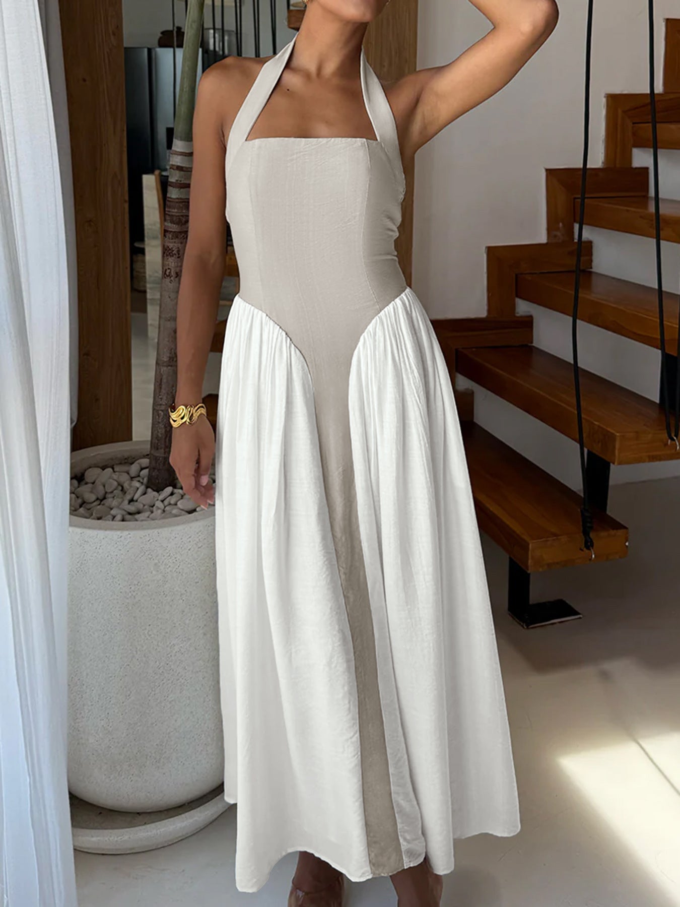 Woman wearing a beige halter neck dress with a white skirt in an indoor setting.