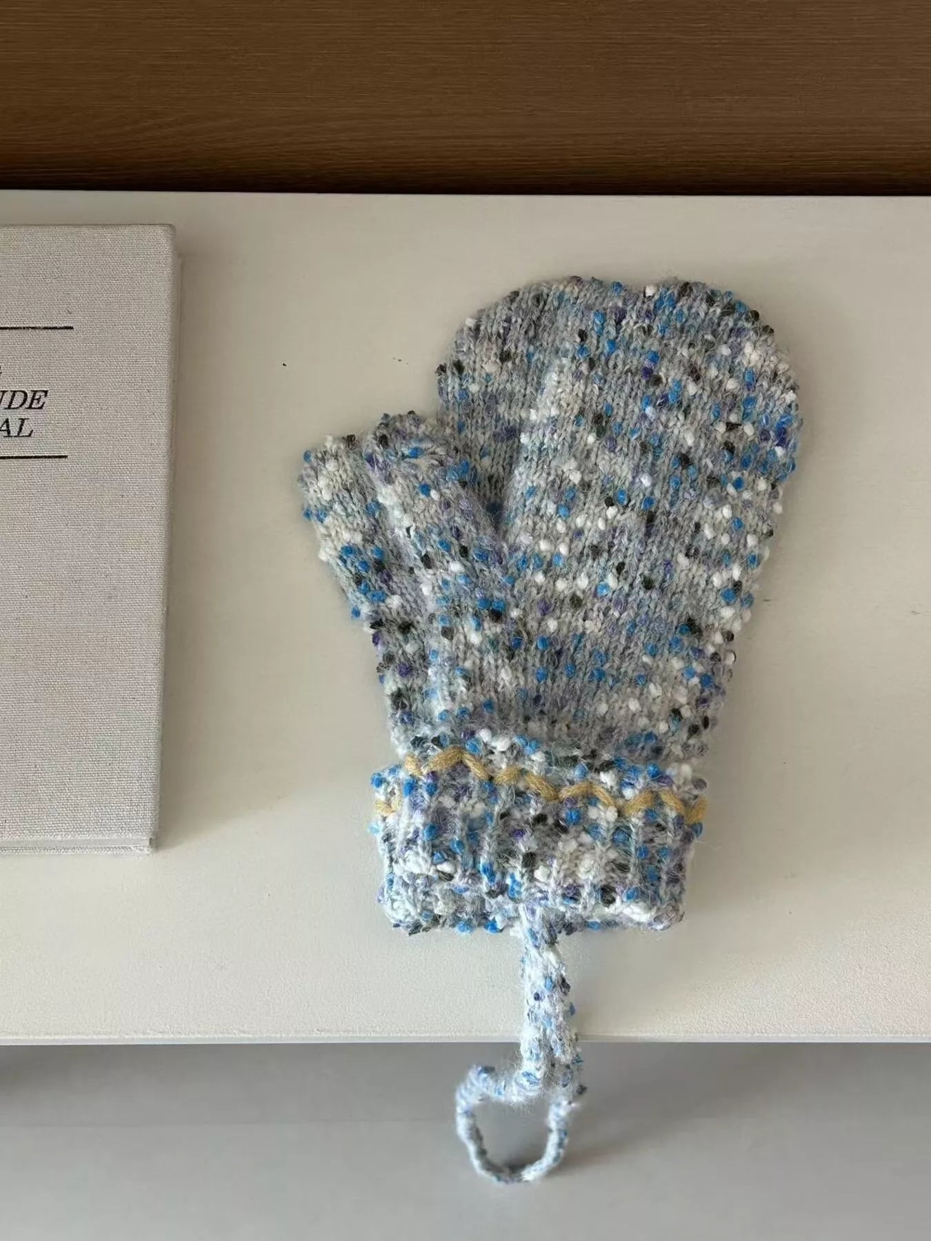 Knitted baby bootie with blue and gray pattern on a white surface