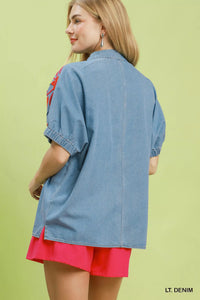 Woman wearing a light denim jacket over a pink dress on a green background