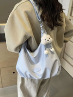Person wearing a beige hoodie with a light blue bag featuring a cloud charm.
