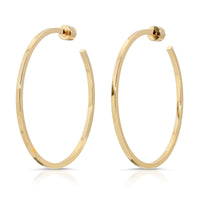 A pair of gold-colored hoop earrings with a square wire design, crafted from recycled brass.