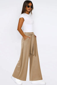 Woman wearing a white top and beige wide-leg pants on a white background
