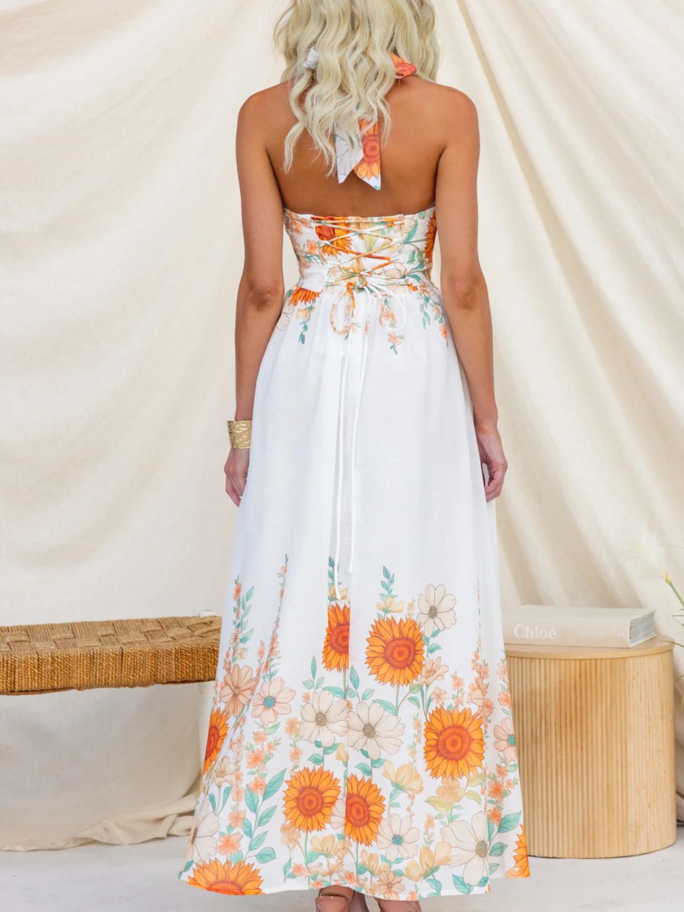 Woman wearing a strapless floral dress with orange flowers against a neutral background