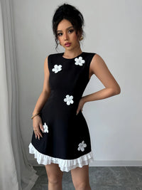 Woman wearing a black dress with white floral patterns against a neutral background