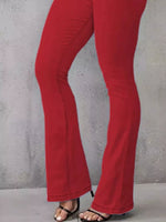 Red pants worn by a person against a gray concrete wall.
