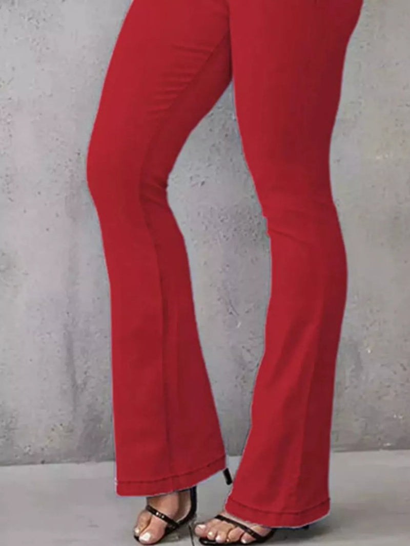 Red pants worn by a person against a gray concrete wall.